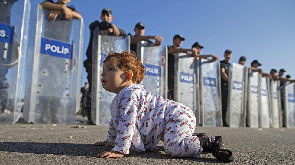 Syrian toddler plays in front of Turkish riot police near the border with Greece - 19 September