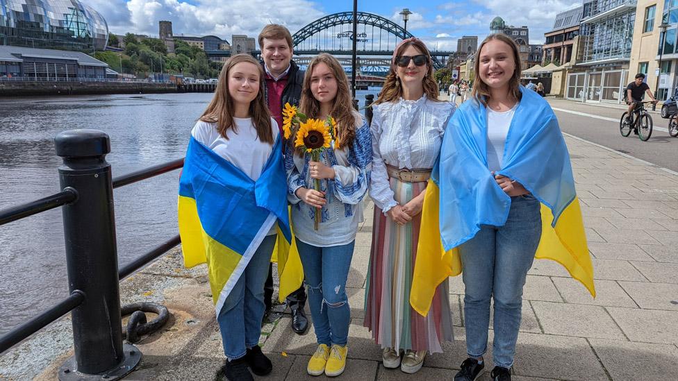 Members of a Ukrainian choir with Newcastle Cllr Alex Hay on the city's quayside