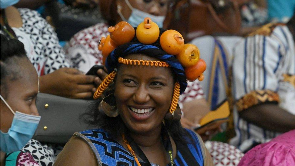 A woman smiling with a head dress of fake oranges