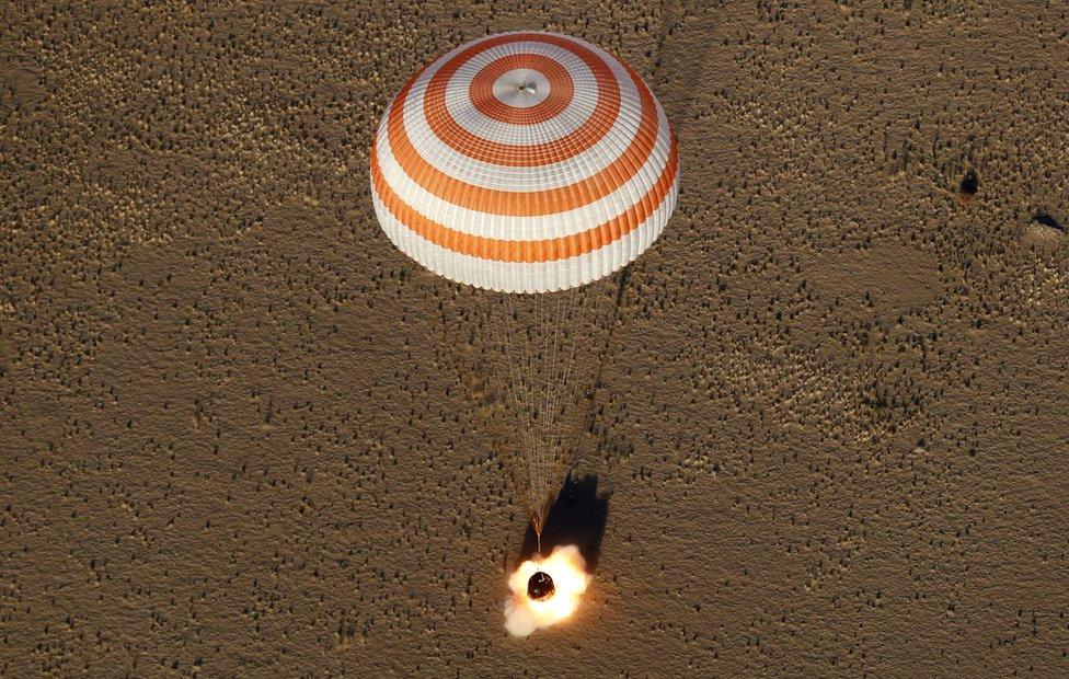 A capsule with a parachute lands in the desert