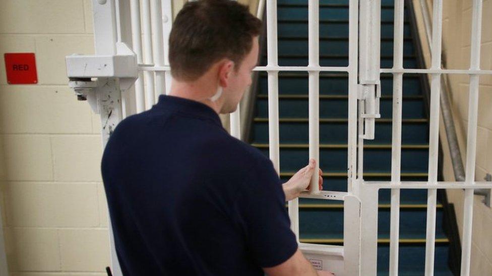 A prison officer locking a gate