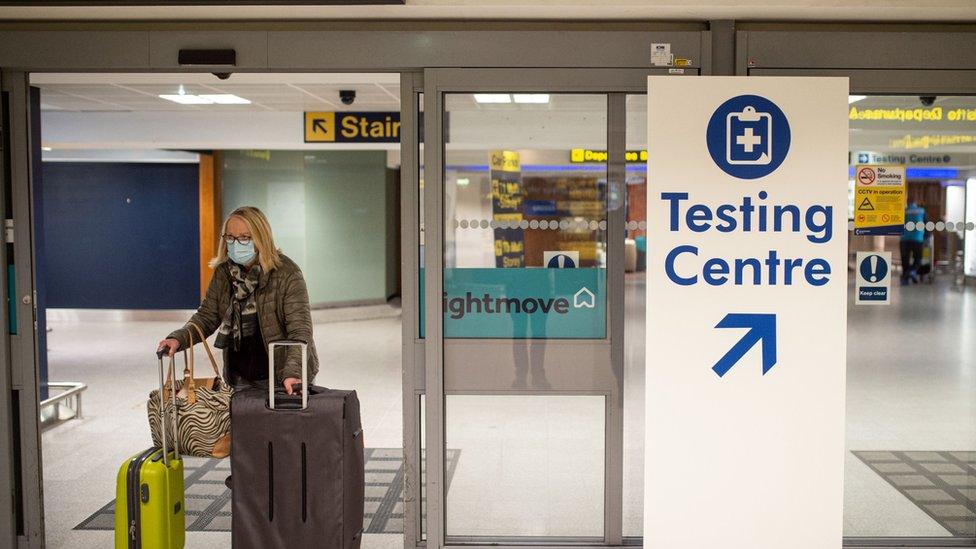 A passenger walks past a sign directing people to a novel coronavirus Covid-19 testing site adjacent to Terminal 1 of Manchester Airport in Manchester, northern England on December 3, 2020.