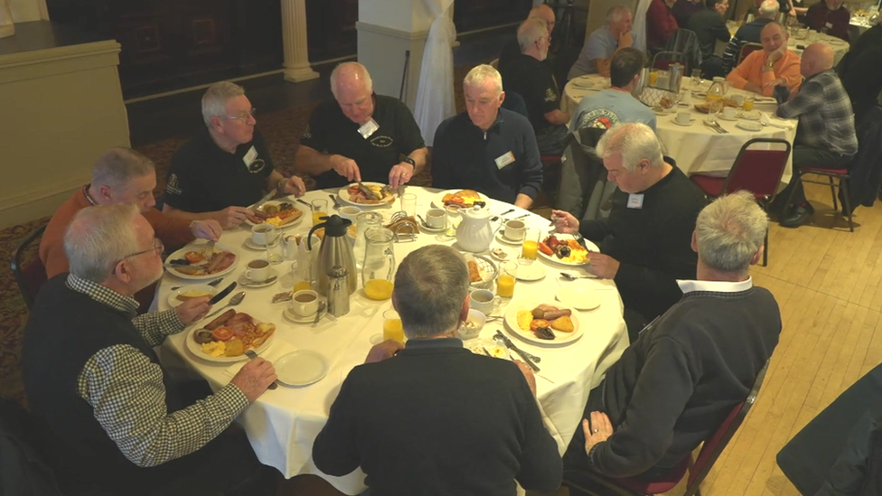 Club members sitting around a table eating breakfast