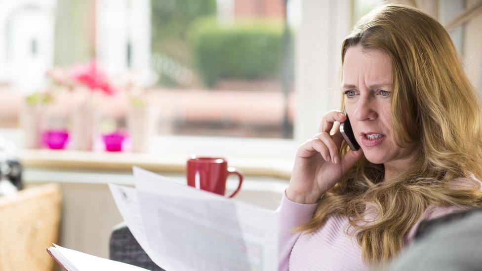 Woman frustratedly calls company on the phone while holding a bill