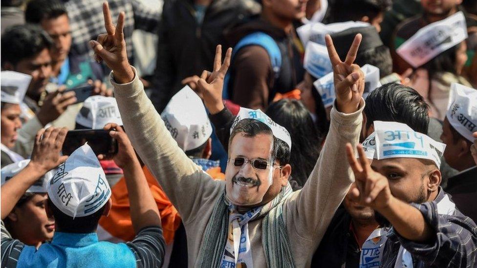 An Aam Aadmi Party (AAP) supporter wears a mask of party chief Arvind Kejriwal while celebrating with others at the party headquarters in New Delhi on February 11, 2020