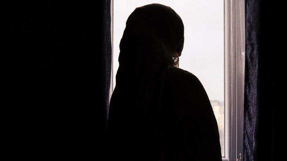 Woman silhouetted by a window