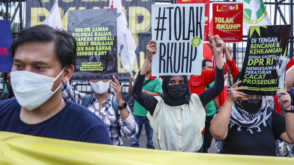 Protesters hold placards rejecting the draft of a new criminal law during a protest outside the parliament building in Jakarta, Indonesia, 05 December 2022.