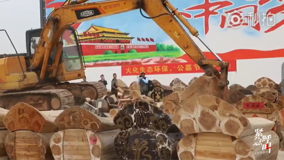 A digger demolishing caskets