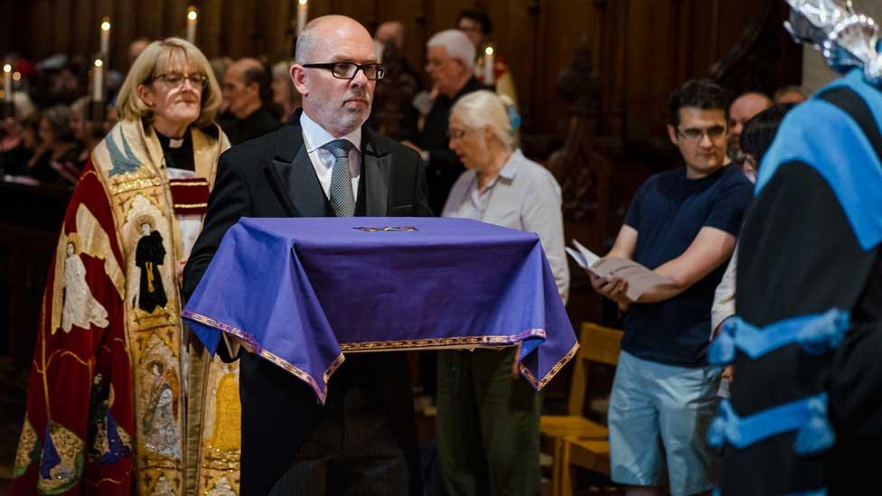 Abbot John's ossuary is carried to the presbytery