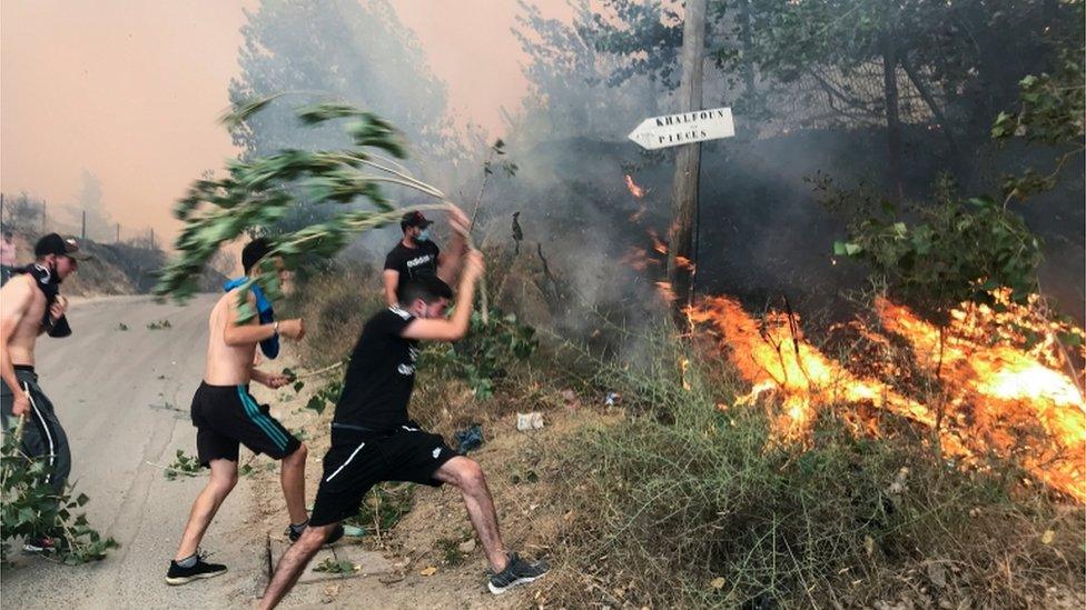 People attempt to put out a fire in the mountainous Tizi Ouzou province, east of Algiers, Algeria August 10, 2021