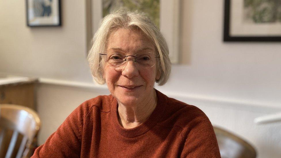 A portrait photo of Anna Hughes sat down in her home