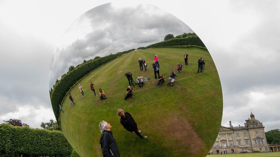 Artist Anish Kapoor looks into his sculpture "Sky Mirror" at Houghton Hall