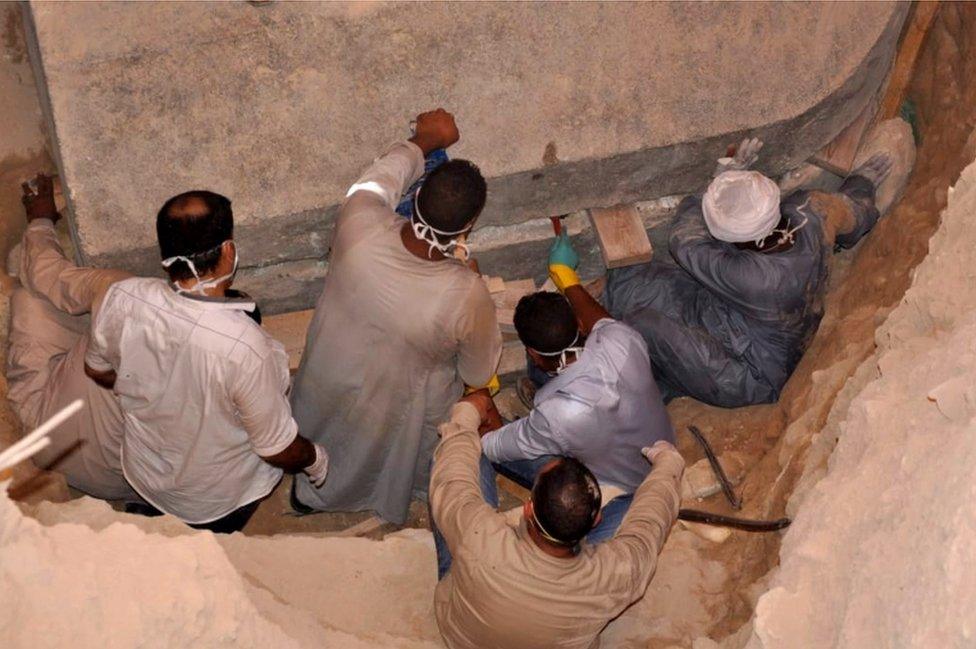 A photo from the Egyptian Ministry of Antiquities shows workers preparing to open the black granite sarcophagus