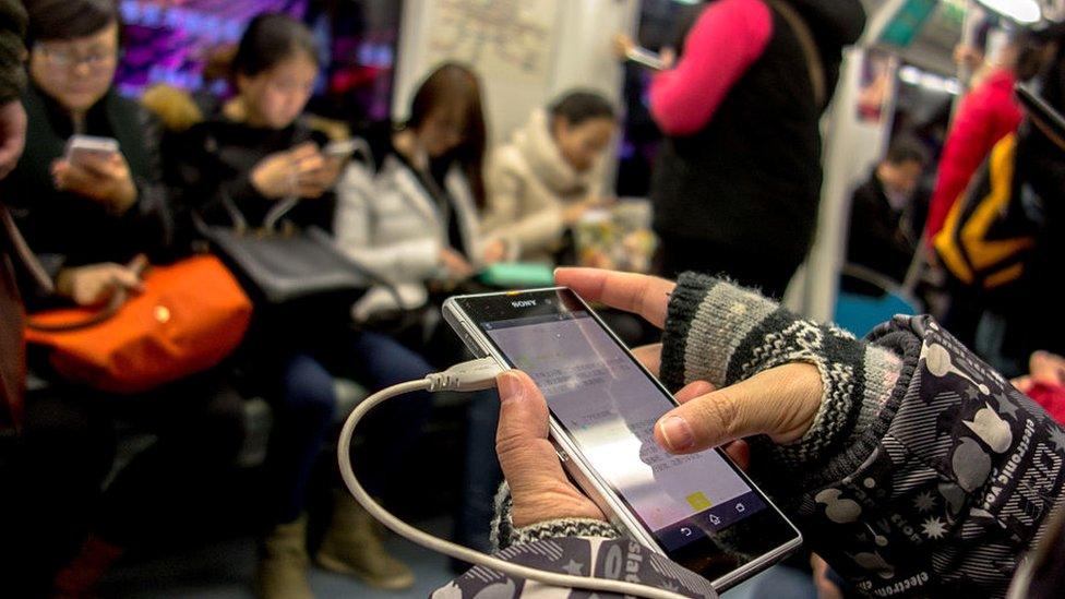 Passenger holding mobile while on Beijing subway