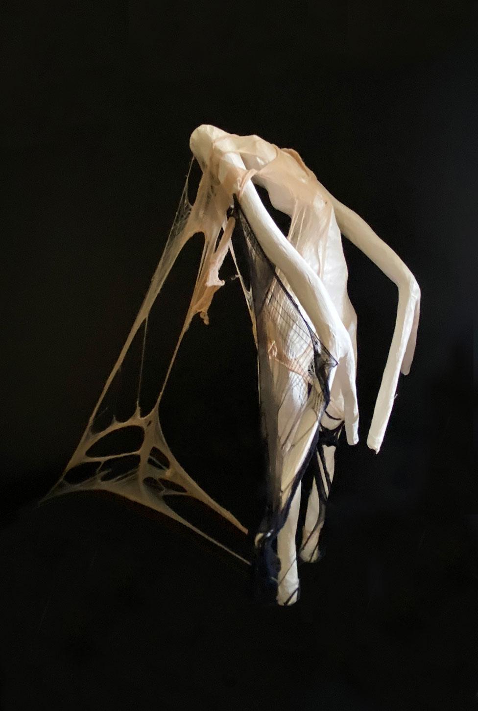 A piece of art showing a sculpture of a mannequin with stretched and torn material on it