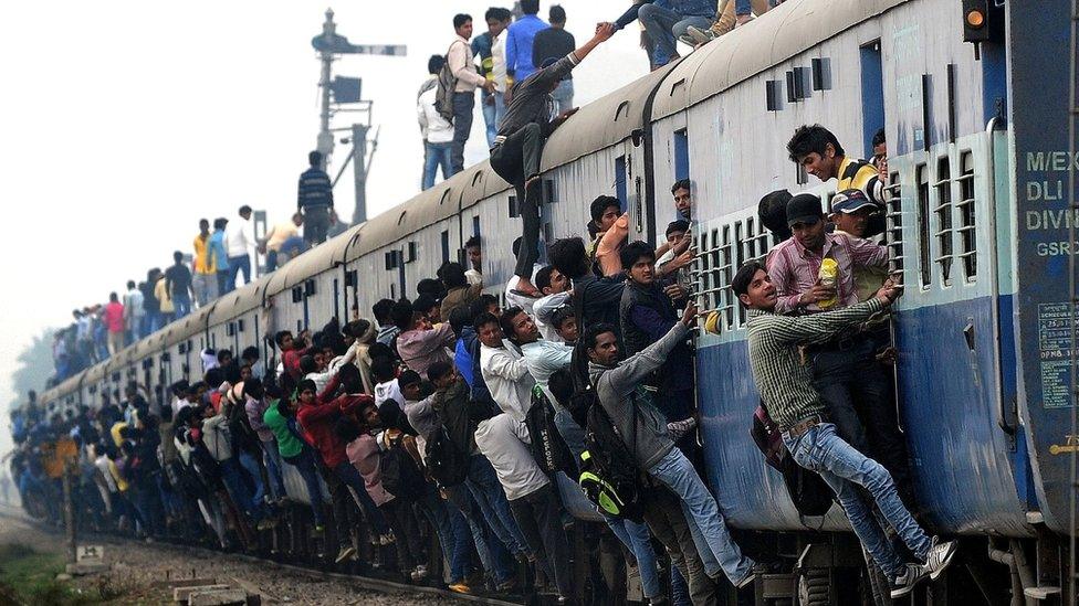 People hanging on to the outside of a train in India