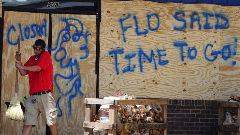 A man sweeps the entrance of a boarded up store