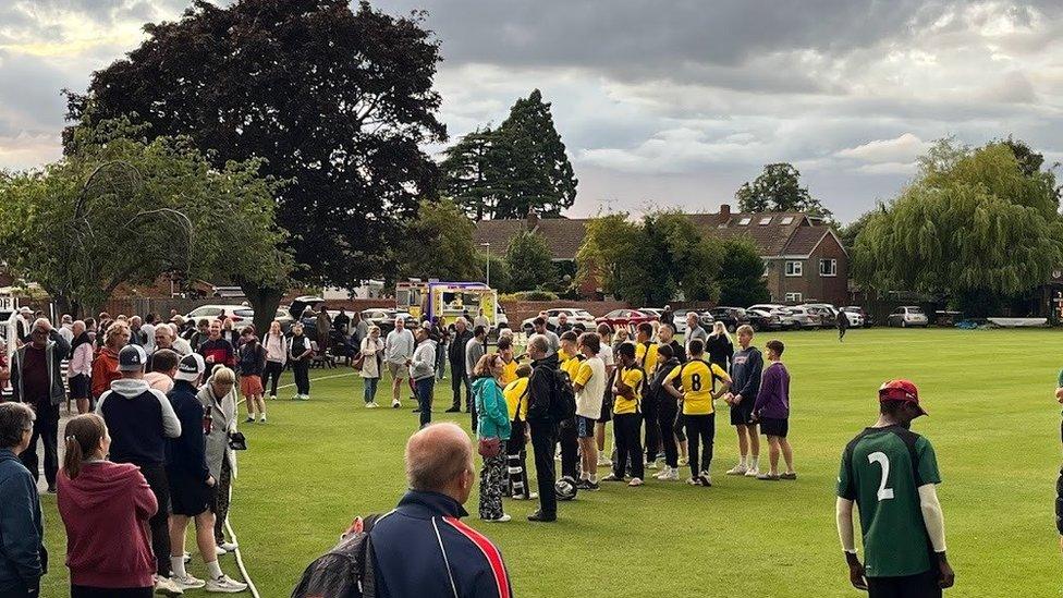 People gathered on lawn outside the cricket ground