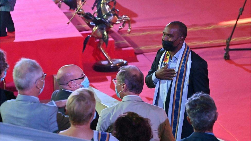 Burkina Faso's foreign minister greeting ambassadors. They are wearing masks, and the minister has his hand on his chest.