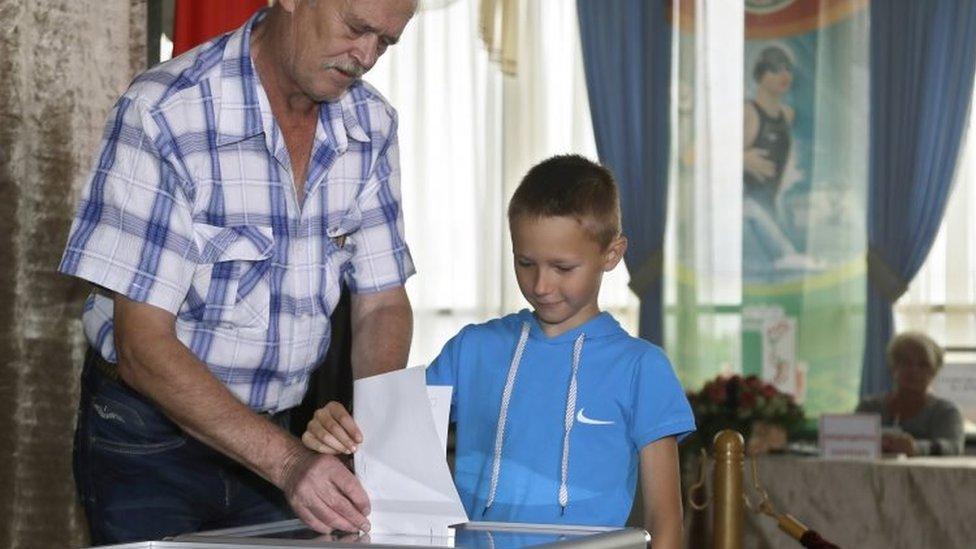 A Belarusian man casts his ballot with a boy at a polling station during parliamentary elections in Minsk (11 September 2016)