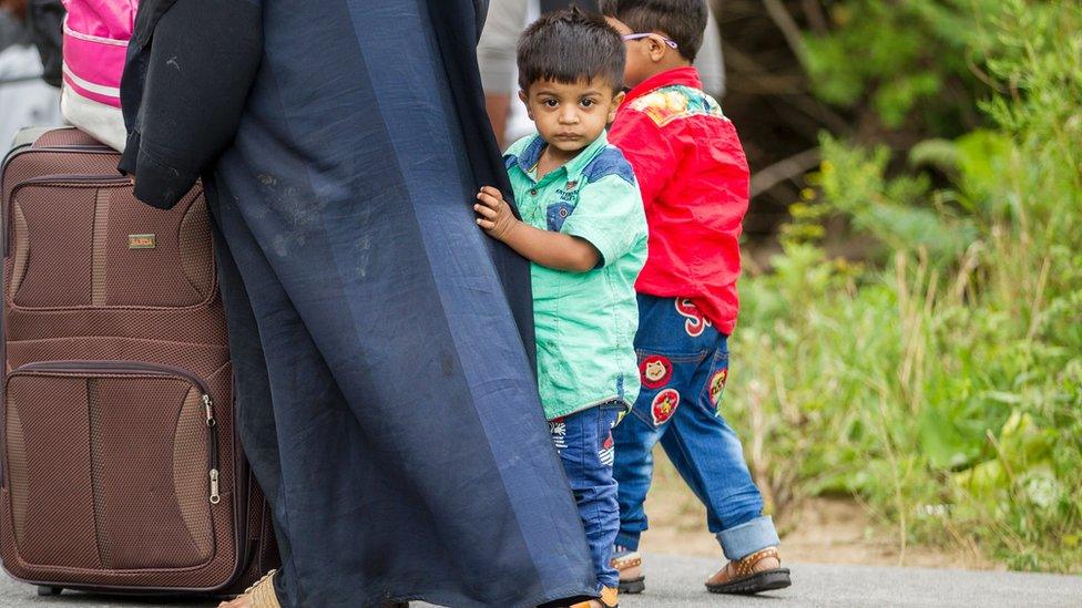 A long line of asylum seekers wait to illegally cross the Canada/US border near Champlain, New York