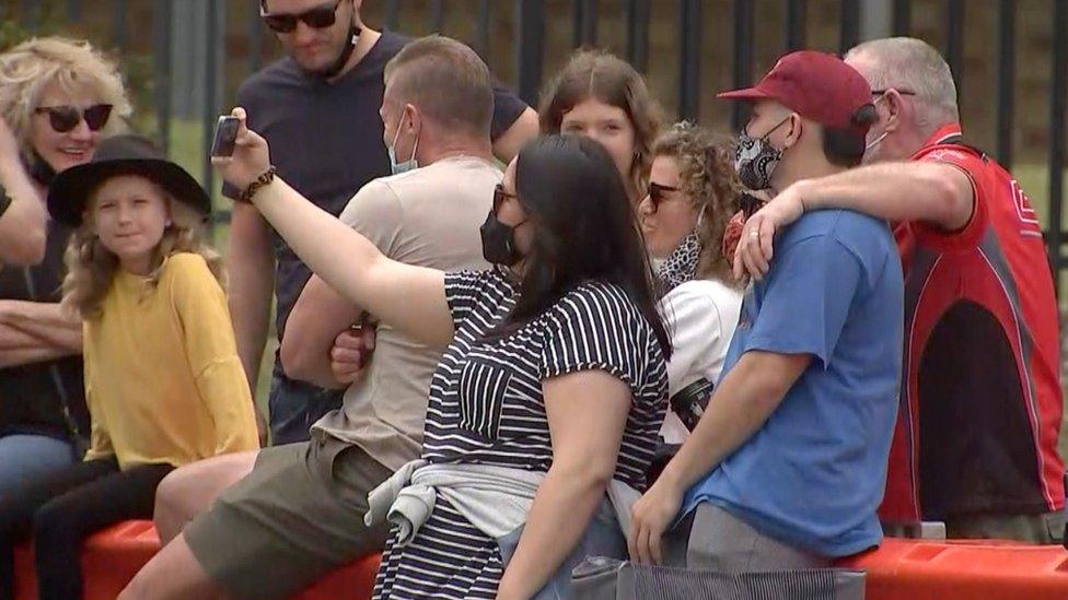 People take selfies over the border barricade