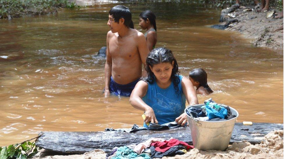 Awa wash clothes in a river in 2014