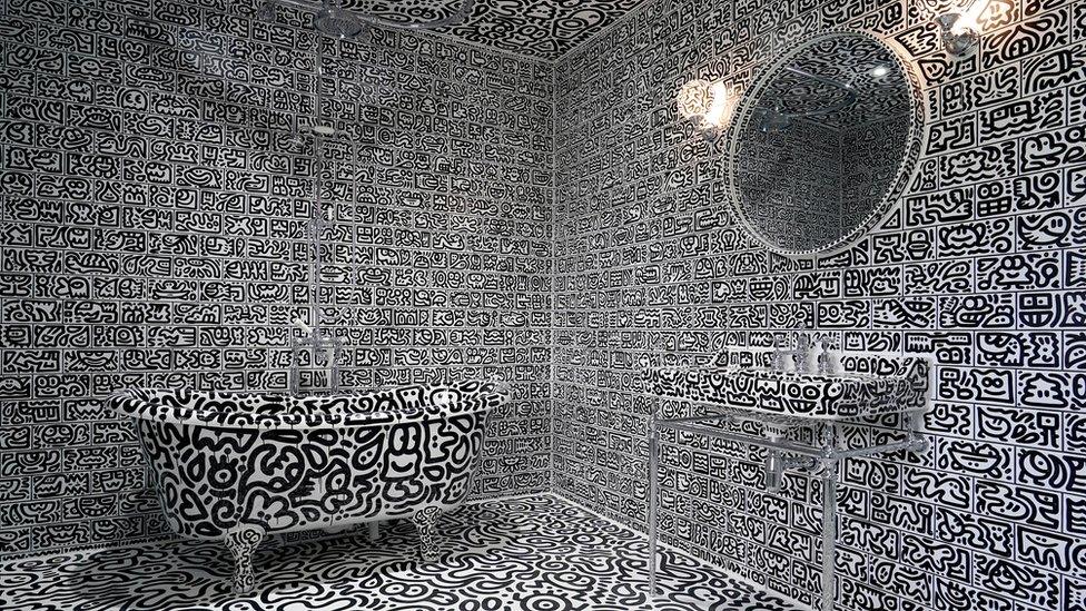 a bathroom including a bath tub and a sink covered in doodles