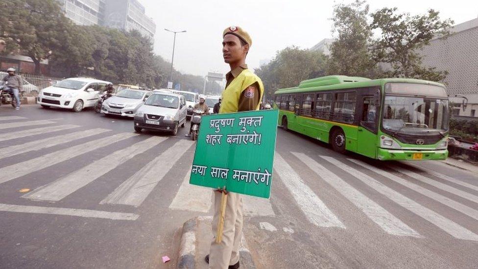 An Indian civil defence volunteer holds a placard reading "We will make our city Pollution free and celebrate the new year" during the fourth day of the implementation of the odd-even pollution reduction scheme for vehicles in New Delhi, India, 04 January 2016.