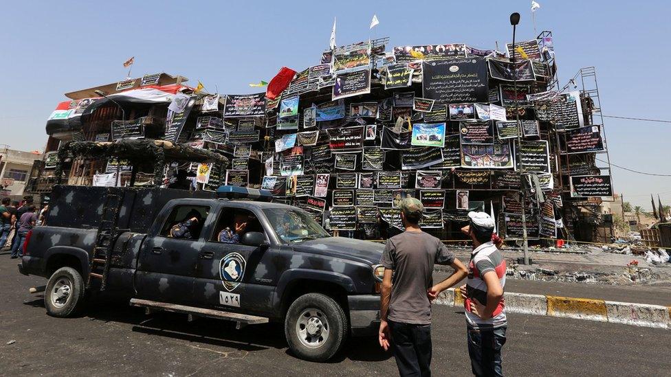 Iraqi security forces drive past scene of suicide bombing in Baghdad's Karrada district (7 July 2016)