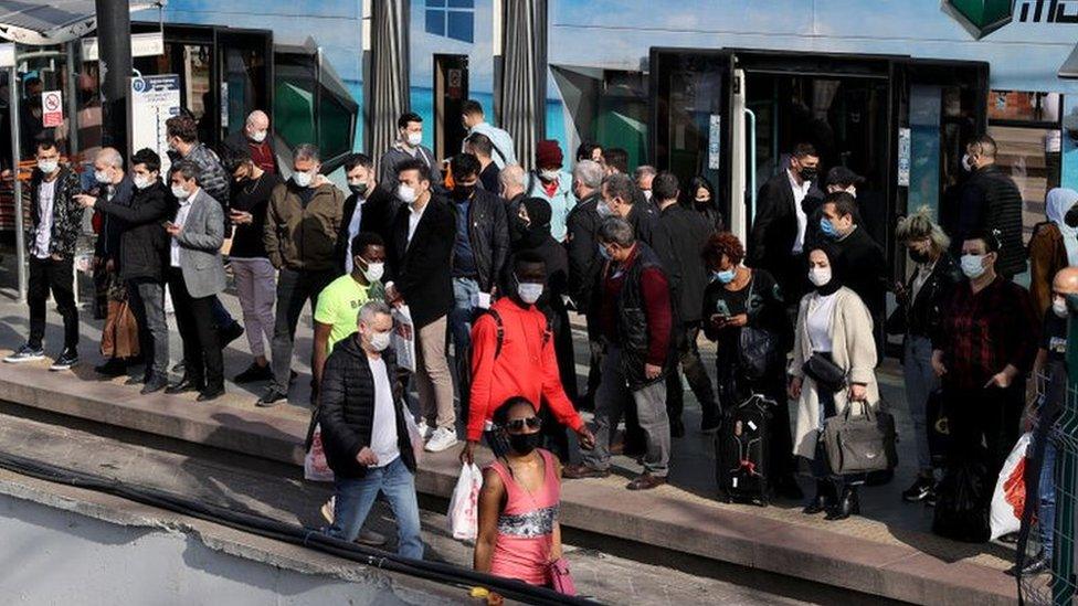 People wait in a queue at Cevizlibag district to get on metrobuses and trams to return their homes on 29 April