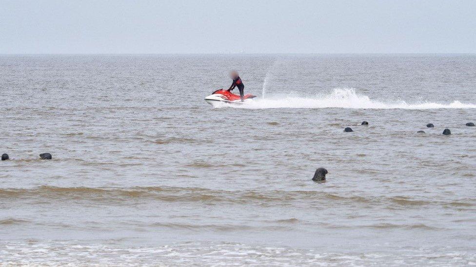 Jet-skier and seals in water off Horsey beach in Norfolk