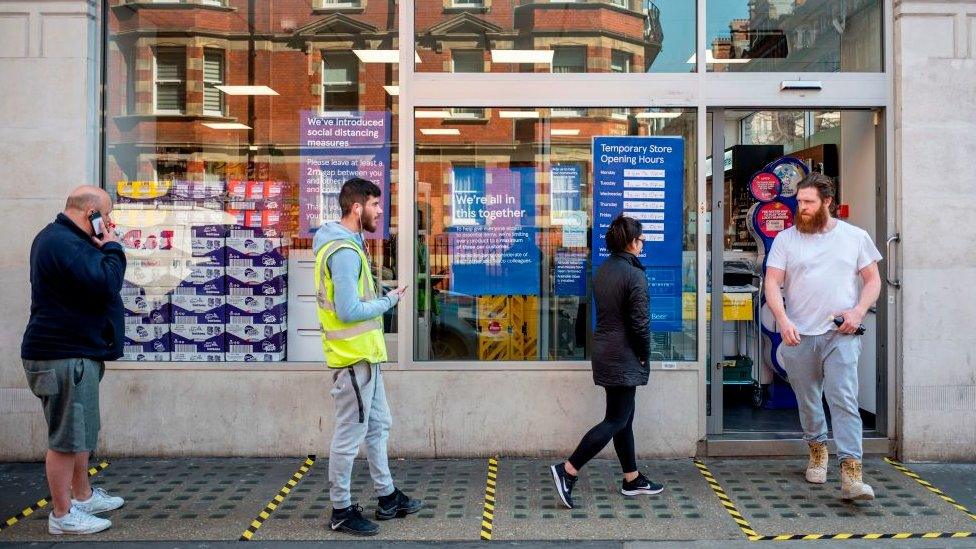 People queuing spaced apart outside a supermarket