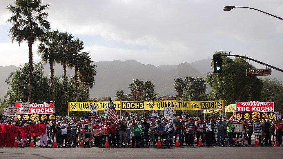 Protesters hold signs that say 'quarantine the kochs''