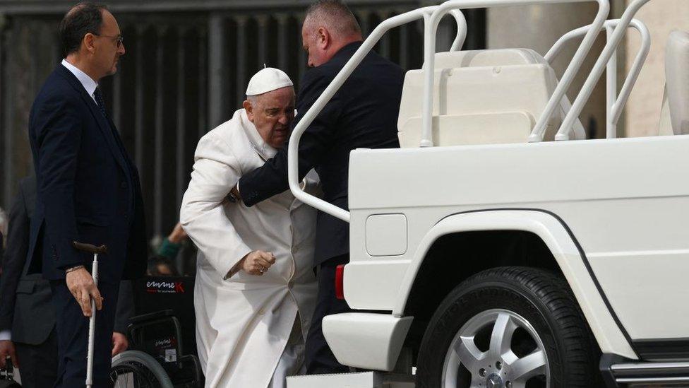 Pope Francis is helped get up the popemobile car as he leaves on March 29, 2023 at the end of the weekly general audience at St. Peter's square in The Vatican