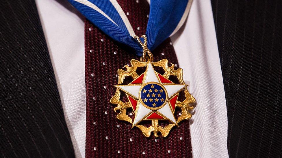 US Presidential medal of freedom hanging over a red tie