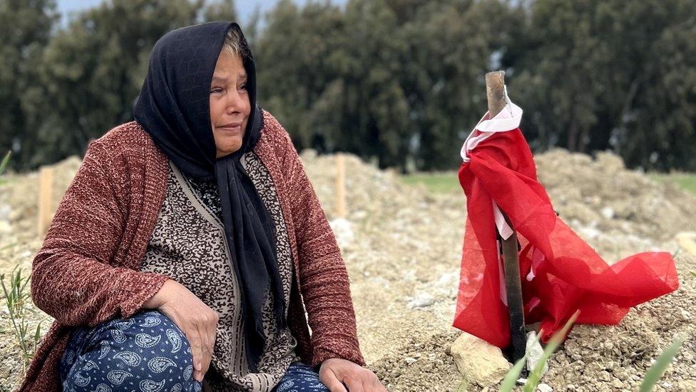 Fethiye Keklik mourns her son next to a Turkish flag