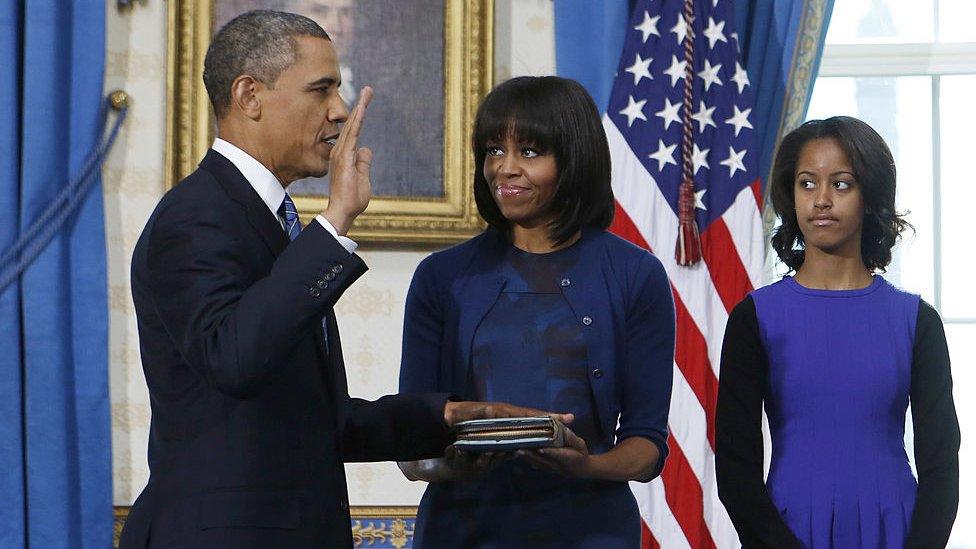 President Barack Obama (L) takes the oath of office in 2013 as first lady Michelle Obama (C) holds the bible as daughter Malia looks on in Washington, DC.