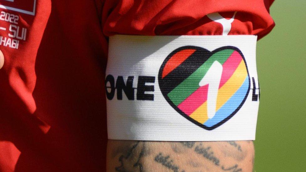 The OneLove armband on a player's arm, featuring a rainbow heart and the number one