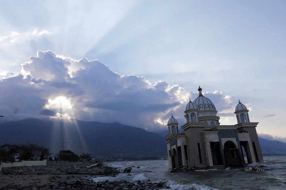 A mosque is seen on a beach amid strewn debris