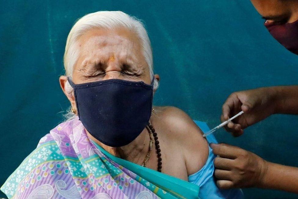 A woman reacts as she receives a dose of COVISHIELD, a coronavirus disease (COVID-19) vaccine manufactured by Serum Institute of India, at a vaccination centre in Ahmedabad, India, March 27,