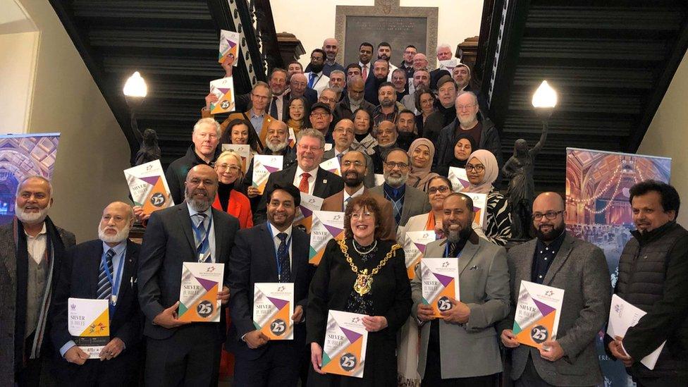 A large group on the stairs of Ipswich town hall holding copies of their new book.