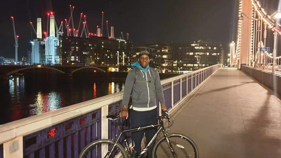 Oladeji Omishore pictured holding a bike on Chelsea bridge