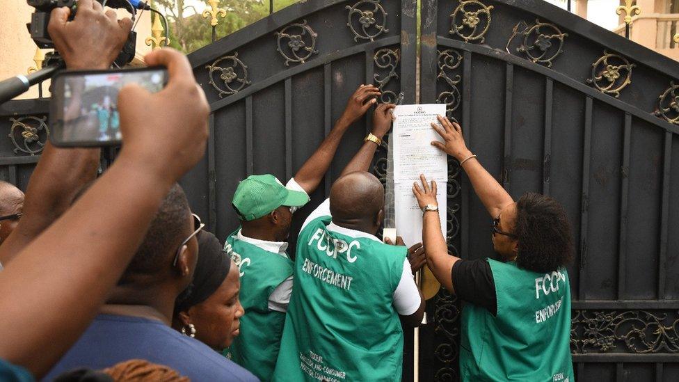 Officers from Nigeria's Federal Competition and Consumer Protection Commission outside the supermarket closed in Abuja over racism allegations