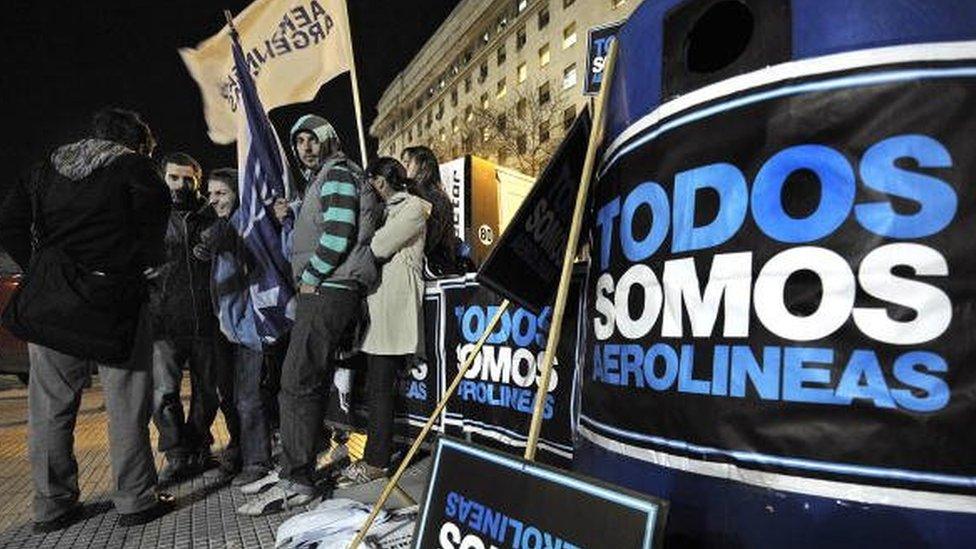 Employees of Aerolineas Argentinas airline wait in front of the Congress building where senators prepare to turn into law a project to nationalize Aerolineas Argentinas. The sign reads, 'We are all Aerolineas [Argentinas].'