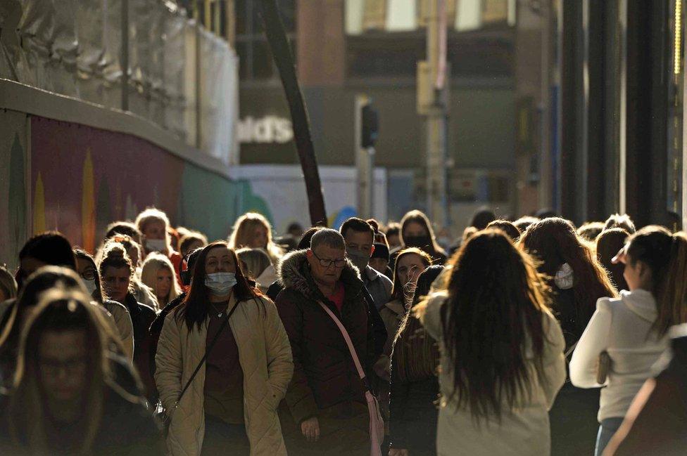 Dozens of shoppers walk along a street in Belfast