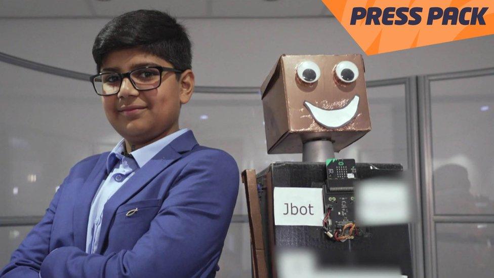 Jay and a robot with a orange Newsround press pack strap on the top right hand side