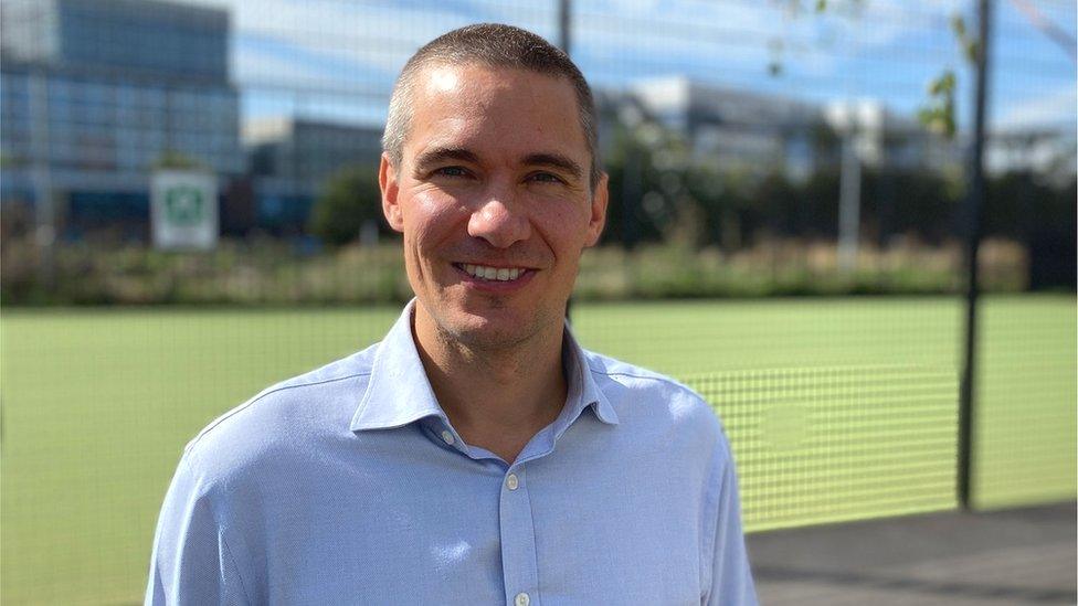 Jamie Masraff, chief executive of the charity OnSide, in front of a green field and a school behind