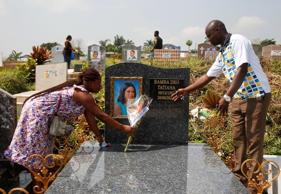 Bolou Marie Marcele puts flowers on the grave of her friend in Abidjan, Ivory Coast.