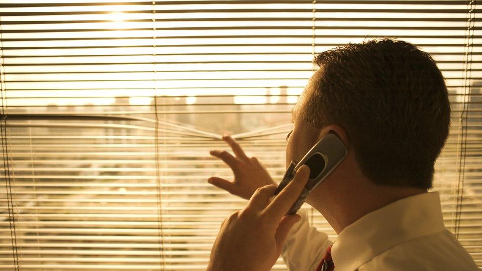 Businessman at window using cell phone